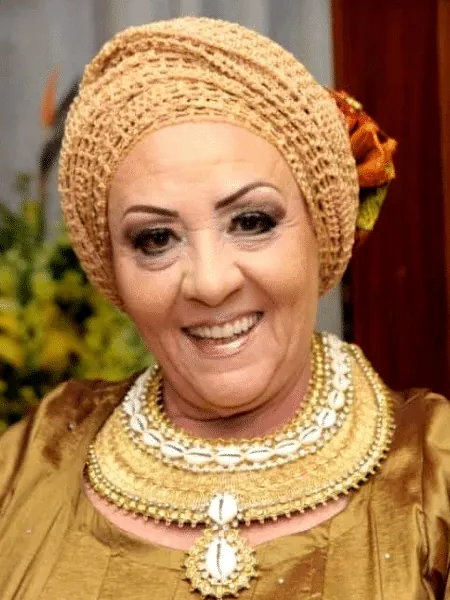 Izza de Oxum sorrindo, com turbante de crochê e colares dourados